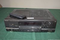 Front view of the Technics SA-GX470 AV control stereo receiver showing control panel, buttons, knob and included remote control on top.