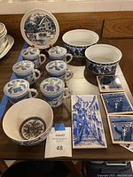 Full view of all items arranged on table: coasters, tea cups with lids, ceramic bowls, decorative plate, porcelain bowl