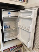Kenmore mini fridge interior with freezer compartment, wire shelves, and vegetable drawer.