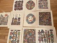 Photo shows the full set of ten colorful original art pieces by James Steel Smith arranged on a wooden floor, featuring buildings, animals, and abstract shapes.