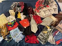 Multiple women's scarves, neck scarves, and pocket squares in assorted colors and patterns spread on surface.