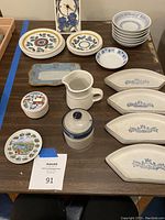 Overview of lot with various vintage Platzgraff and other ceramic dishes, bowls, and kitchenware arranged on table including salad plates, small bowls, rectangular plates, porcelain dish, and clock.