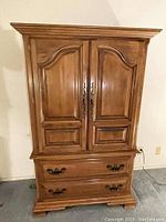 Front view of wooden dresser with two closed paneled doors and two lower drawers with metal handles.