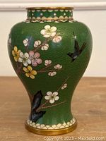 Front view showing green background with multicolored flowers and a black bird in flight.