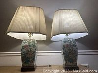 Two lamps on wooden surface, lit with shades