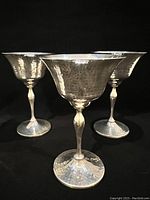 Front close-up view of three hammered silver port glasses showing textured detail and reflections.