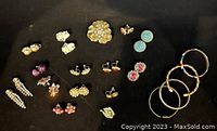 Top view of assorted vintage earrings and metal bangles on black background.