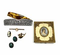 Top view photo showing complete set consisting of silver comb, cameo pin, carved ivory bar pin, green scarab cufflinks, gold cufflink, and miniature portrait in gold/ivory frame.