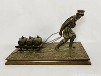Front view of full sculpture showing man pulling sled with three kegs on rectangular base.