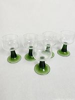 Five green beehive stemmed vintage Roemer wine glasses arranged in a staggered formation.