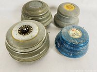 Four antique aluminium music boxes grouped together showing varying lid designs and finishes.
