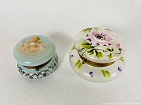 Top and angled views of two antique puffy glass trinket boxes showing enamelled decoration and brass mounts.