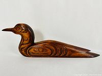 Side view of the duck carving showing detailed Coast Salish style engravings and smooth wood finish.