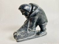 Front and side view showing figure in parka leaning over a sled on a flat base.