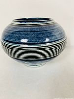 Front view of the round pottery vase showing the blue gradient glaze and horizontal incised lines.