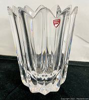 Clear crystal vase with sharp angular vertical scalloped ridges forming a floral star shape, red Orrefors Sweden label visible near the top edge.