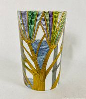 Front view of cylindrical porcelain vase decorated with colorful, stylized pop art trees with gold details.