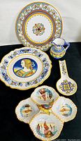 Photo of the full set showing five decorative ceramic pieces: two plates, a jug, a spoon rest, and a divided shell dish, all hand painted with Deruta style motifs.