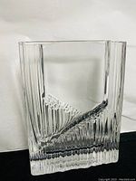 Front and side views of the clear crystal vase exhibiting its vertical ridged pattern and wave design.