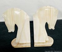 Front angle view showing the horse head profiles and the polished onyx material with natural variegation.
