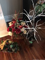 Overview photo showing the red and cream flowers in a basket beside the frosted white branches in a black base.