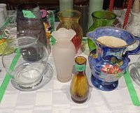 All five glass vases and the blue floral KOS England ceramic pitcher arranged on tablecloth.