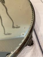 Close-up of the scalloped cut glass edge of the Victorian mirrored cake stand showing wear and a missing foot attachment point.