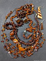 Overview of assorted amber jewelry including necklaces, earrings, and pendants spread on gray background