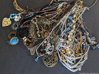 Photo showing a tangled collection of various Avon signed necklaces with assorted pendants, beads, and chains in multiple metal tones and colors.