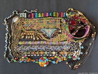 Full view of assorted colorful rhinestone costume jewelry including necklaces and bracelets arranged on dark background.