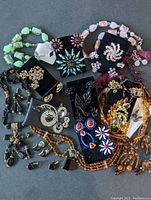 Full assortment of colorful costume jewelry sets with various earrings, brooches, and necklaces displayed on black velvet easels.