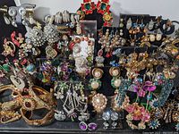 Full collection of assorted costume earrings displayed on black earring stands showing a wide variety of styles including rhinestones, pearls, and colorful beads.