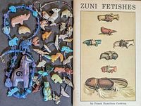 Photo of assorted Native American style carved hard stone animal fetishes, two beaded necklaces with animal pendants, and a book titled 'Zuni Fetishes' by Frank Hamilton Cushing.