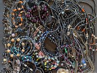 Top view of tangled hematite bead jewelry including necklaces, bracelets, and some earrings with mixed bead shapes and colors