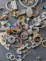 Assortment of mixed metal earrings, pendants, rings, and other jewelry with rhinestones and pearls.