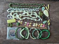 Full set layout showing multiple jade or jade-like stone necklaces, bracelets, pendants, and earrings arranged on a surface.