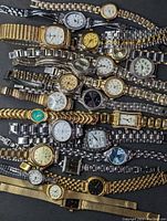 Top-down view of assorted ladies wristwatches mixed in silver, gold and two-tone bands with various round, square, and rectangular dials