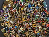 Wide view of assorted lapel pins showing a variety of designs, including cartoon characters, logos, and symbols in a mixture of metal and enamel colors.