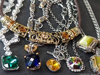 Close-up of necklace pendants showing square cut stones in various colors and metal settings