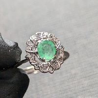 Close-up view of the front face of the ring showing the oval Colombian emerald and diamond halo in solid palladium.