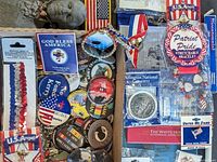 Full view of box containing assortment of patriotic pins, beaded bracelets, White House ornaments with COAs, and Bicentennial Sheaffer pen; many items featuring American flag themes.