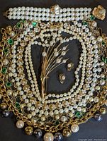 Full view of assorted pearl jewelry including necklaces, bracelet, brooch, earrings, and cocktail ring on dark background.