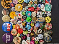 Top view of assorted pinback buttons with various colors and texts including Birthday Boy and Employee of the Month