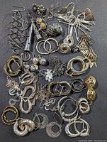 Overview photo showing 35 plus pairs of sterling silver earrings in various styles arranged on a dark surface with visible patina.
