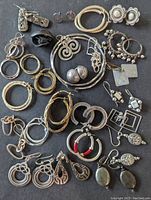 Top view showing all pairs of earrings laid out displaying diverse styles and designs, including hoops, dangles, and studs, varying sizes and patterns.