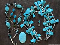 Full view of assorted turquoise and pearl jewelry including necklaces and pendants with sterling silver accents and a pair of earrings