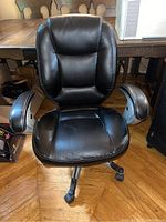 Front view of black office chair showing padded backrest and armrests with visible peeling on vinyl.