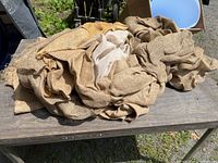 Large pieces of burlap and sheer fabric loosely folded on an outdoor wooden surface
