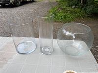 Set of 3 clear glass pieces on table: wide cylinder, tall cylinder, and round bowl