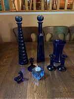 Full collection of cobalt blue glass items displayed on wooden table.